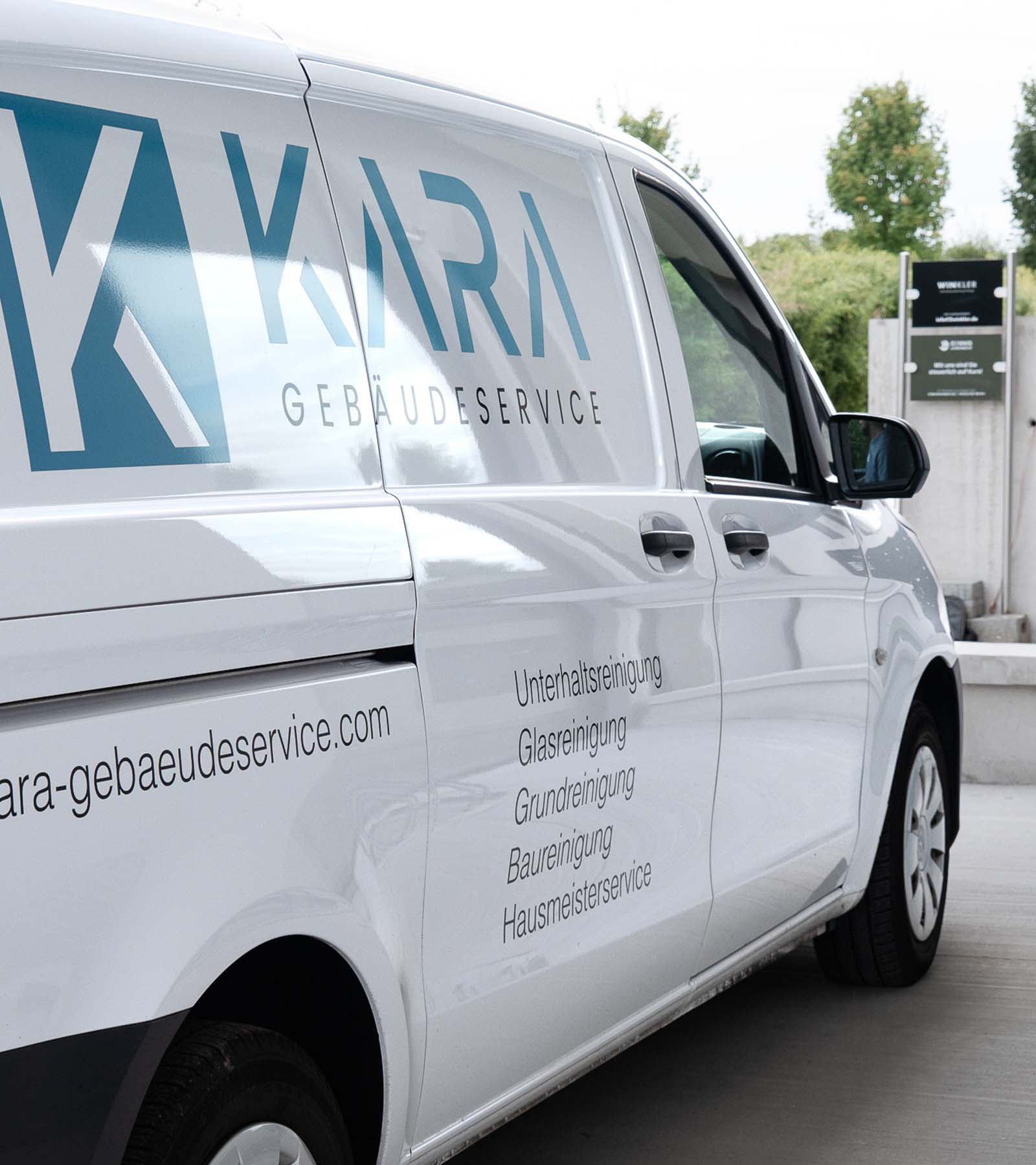 Firmenfahrzeug von KARA Gebäudeservice mit Logo und Leistungsübersicht wie Unterhaltsreinigung, Glasreinigung und Hausmeisterservice