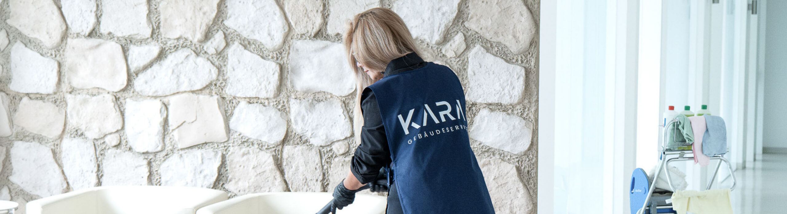 Mitarbeiterin von KARA führt Unterhaltsreinigung durch und saugt in einer Praxis