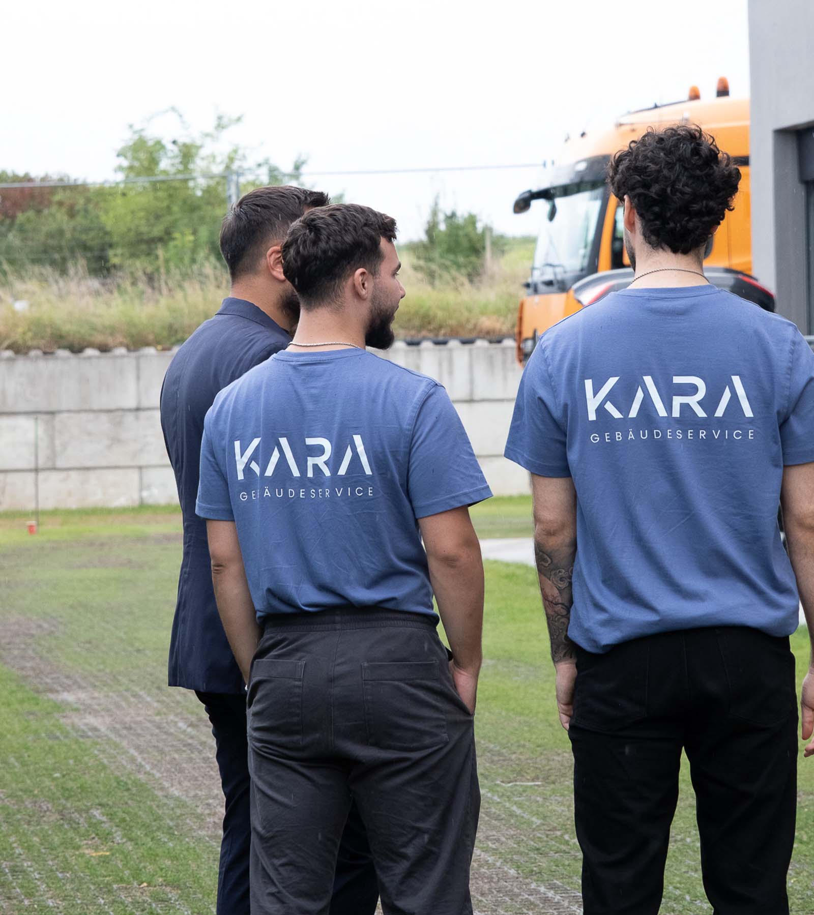 Drei Mitarbeiter von KARA Gebäudeservice stehen zusammen im Außenbereich